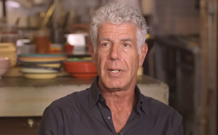 Man with gray hair in a kitchen setting, wearing a dark shirt, representing a nice celebrity according to netizens.