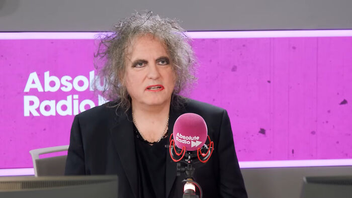 A celebrity at Absolute Radio station, in front of a microphone, speaking during an interview.
