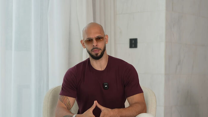 Man in sunglasses discussing assumptions about women, seated in a modern setting with a maroon shirt.