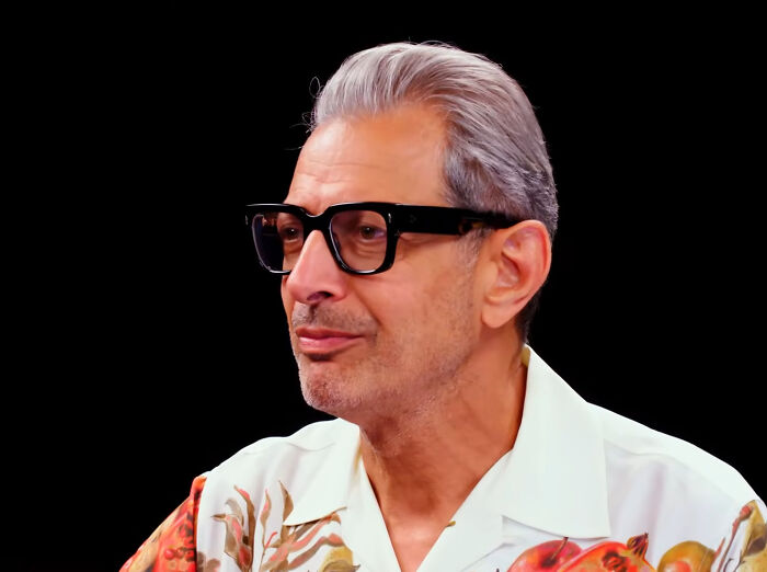 A celebrity with glasses and floral shirt against a black background, representing nicest celebrities according to netizens.