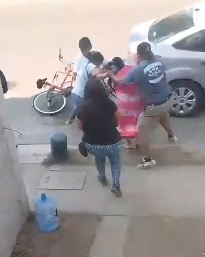 Group confrontation on sidewalk near parked car and bicycle. Group confrontation on sidewalk near parked car and bicycle.