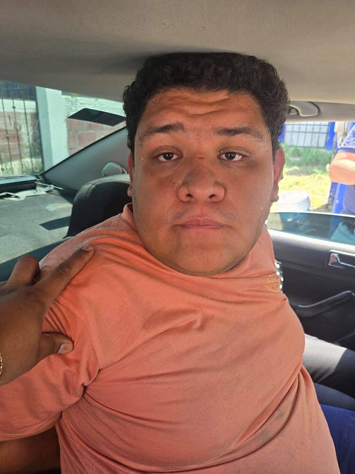 A person in a car wearing an orange shirt, with a hand resting on their shoulder, inside a vehicle. A person in a car wearing an orange shirt, with a hand resting on their shoulder, inside a vehicle.