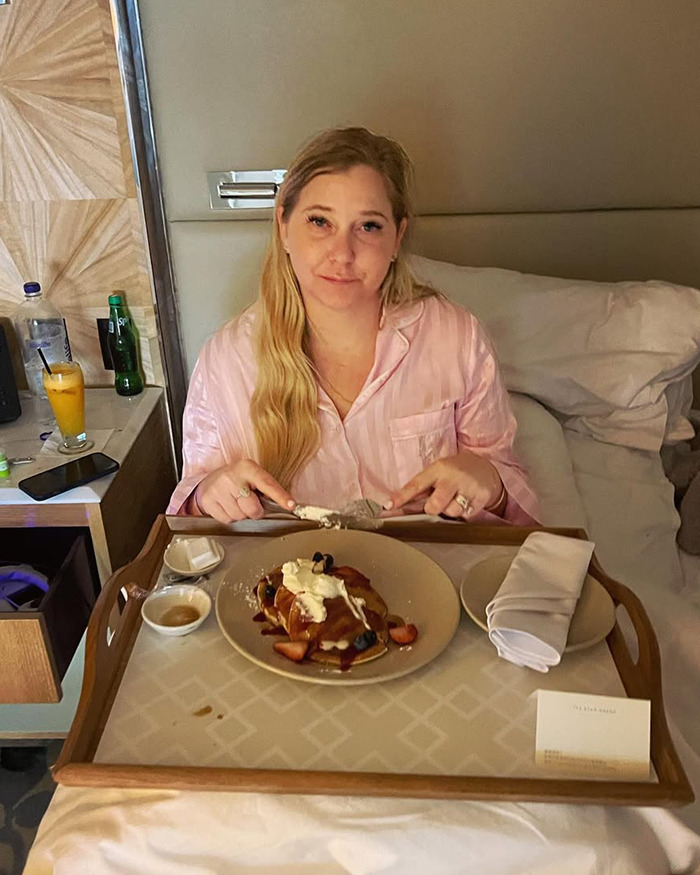 Woman in pink pajamas sitting in bed with breakfast tray, related to Virginia Giuffre’s tragic final note after her death. Woman in pink pajamas sitting in bed with breakfast tray, related to Virginia Giuffre’s tragic final note after her death.