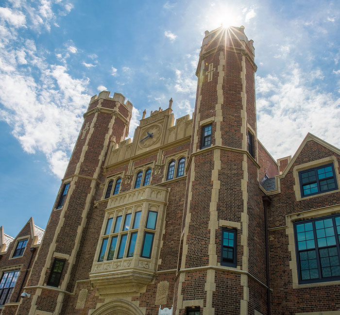 Historic college building with tall towers and sunlight shining, related to trans athlete controversy in women's fencing team.