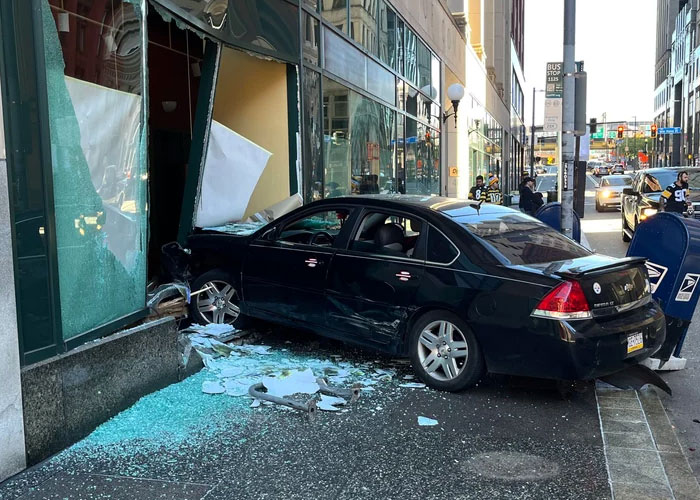 Coche choca contra un edificio, vidrio roto y escombros en la acera, escena de experiencia salvaje urbana.