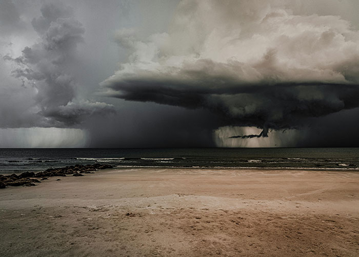 Tormenta salvaje amenazante sobre la playa, olas oscuras y nubes densas presagian un peligro inminente.