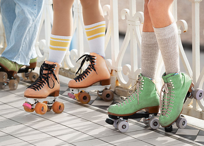 Tres personas con patines retro coloridos sobre un suelo de baldosas blancas, listas para una experiencia salvaje.