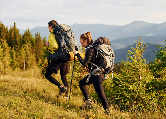 Personas de senderismo en la montaña con mochilas, viviendo experiencias salvajes.
