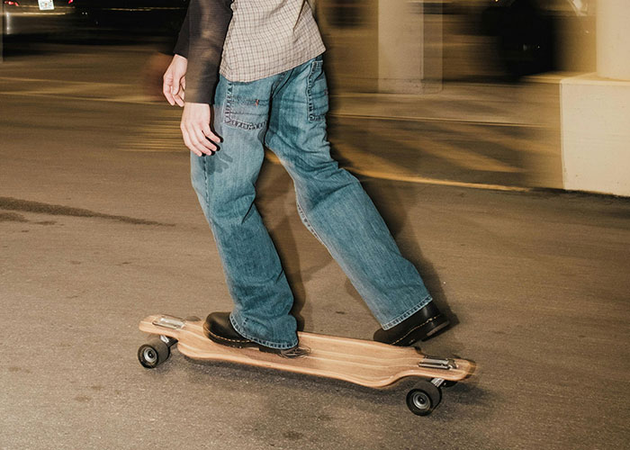 Persona con jeans sobre longboard en movimiento, reflejando experiencias salvajes.