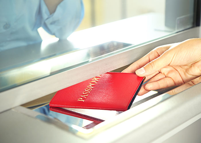 Hand passing a red passport through a counter window, symbolizing intuition to leave a situation safely.
