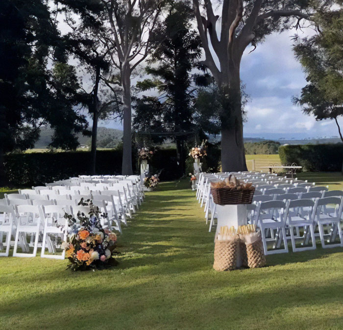 Wedding ceremony setup with white chairs, floral arrangements, and an outdoor backdrop; captures the stunning venue.