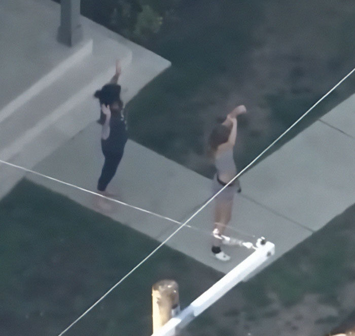 Two people with hands raised during police search related to hit-and-run in LA.