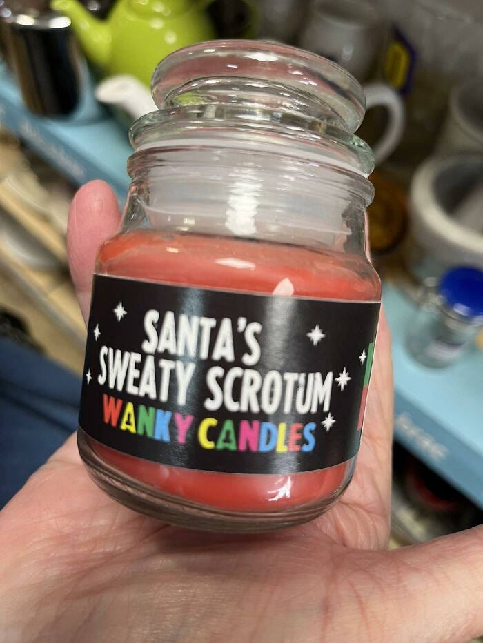 A bizarre candle labeled "Santa's Sweaty S*****m," found in a secondhand shop, held by a person.