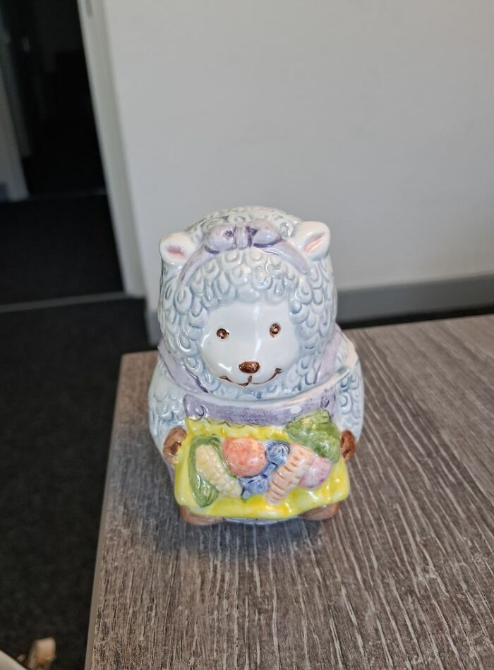 Ceramic sheep figurine holding colorful basket, a bizarre treasure from a secondhand shop.