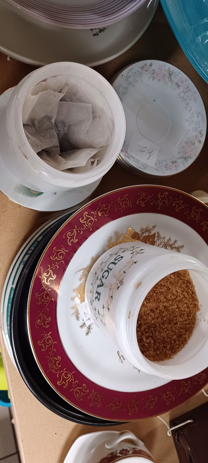 Bizarre secondhand shop treasure: stacked plates with tea bags and sugar in jars.