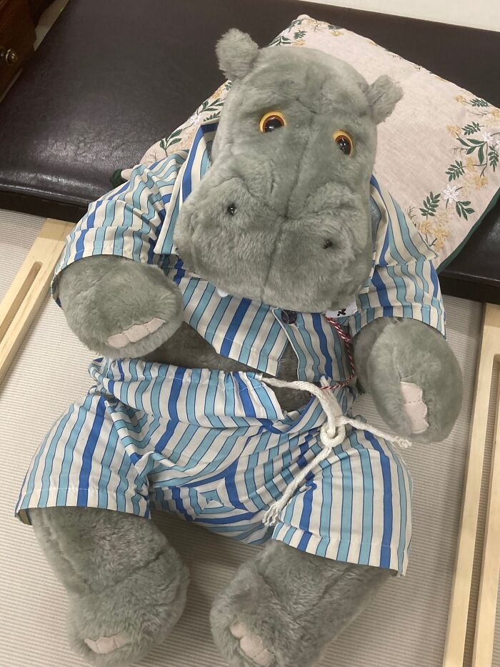 Stuffed hippo in striped pajamas found at a secondhand shop, sitting on a bench.