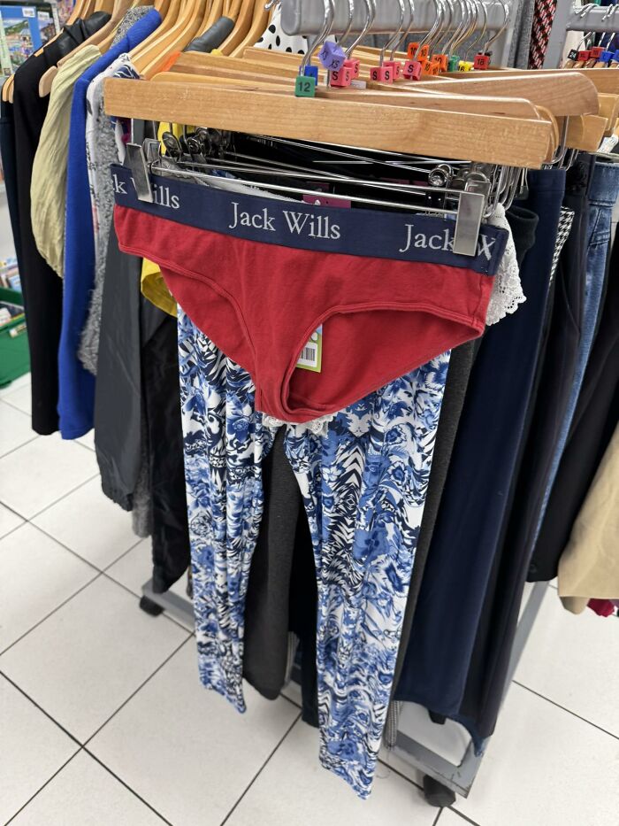 Red Jack Wills briefs over blue patterned leggings on a thrift shop rack, showcasing bizarre secondhand treasures.
