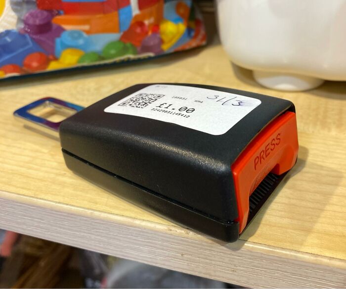 Secondhand shop treasure, a quirky gadget with red button, labeled £1.00, on a wooden shelf.