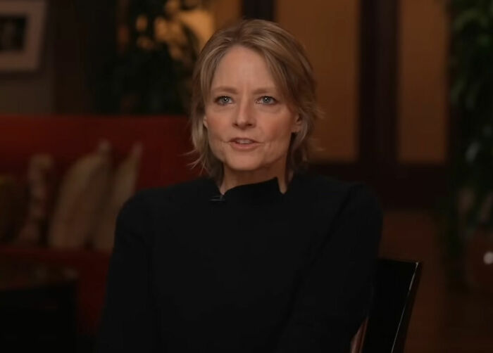 Woman in a black shirt speaking in an interview setting, providing random knowledge insights.