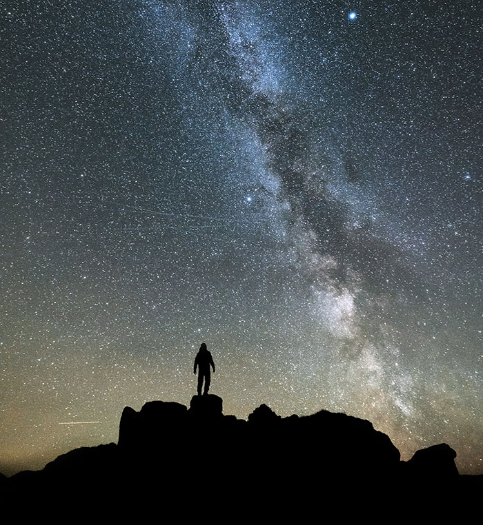Person stargazing under the Milky Way, illustrating a fascinating science fact about the universe's endlessness.