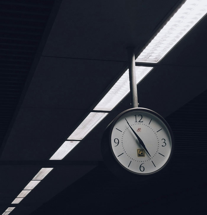 Station clock hanging from the ceiling, showcasing time under fluorescent lights, illustrating fascinating science concepts.