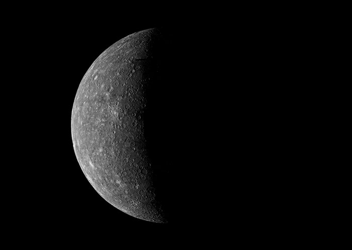 Half-illuminated surface of Mercury in space, showcasing craters and stark contrasts.