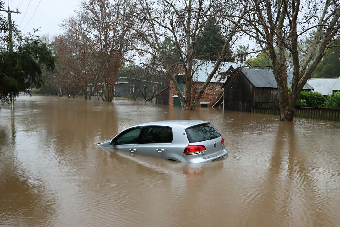 A submerged car in a flooded street, highlighting everyday dangers during heavy rain.