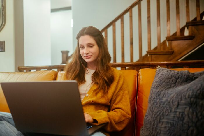 Person sitting on a couch, using a laptop, possibly reading about loopholes online.
