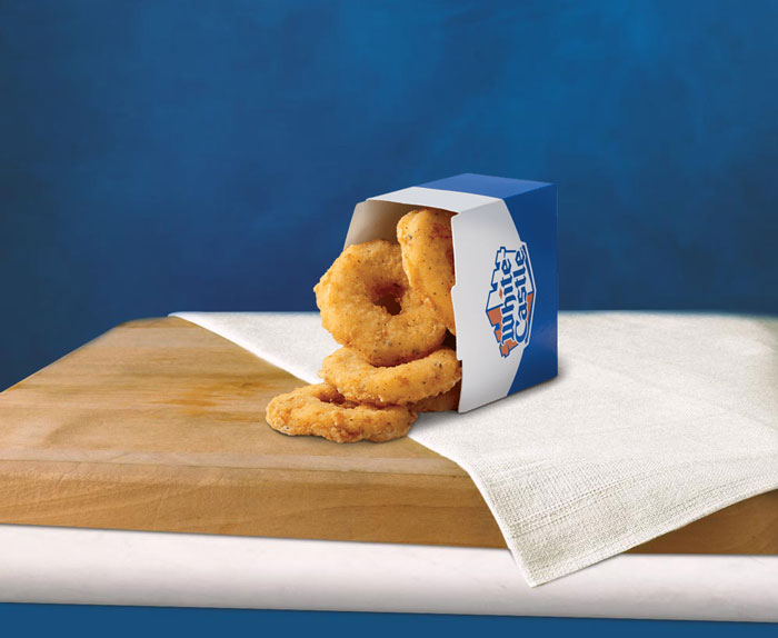 White Castle chicken rings in blue box on napkin, showcasing their $3.99 deal. White Castle chicken rings in blue box on napkin, showcasing their $3.99 deal.