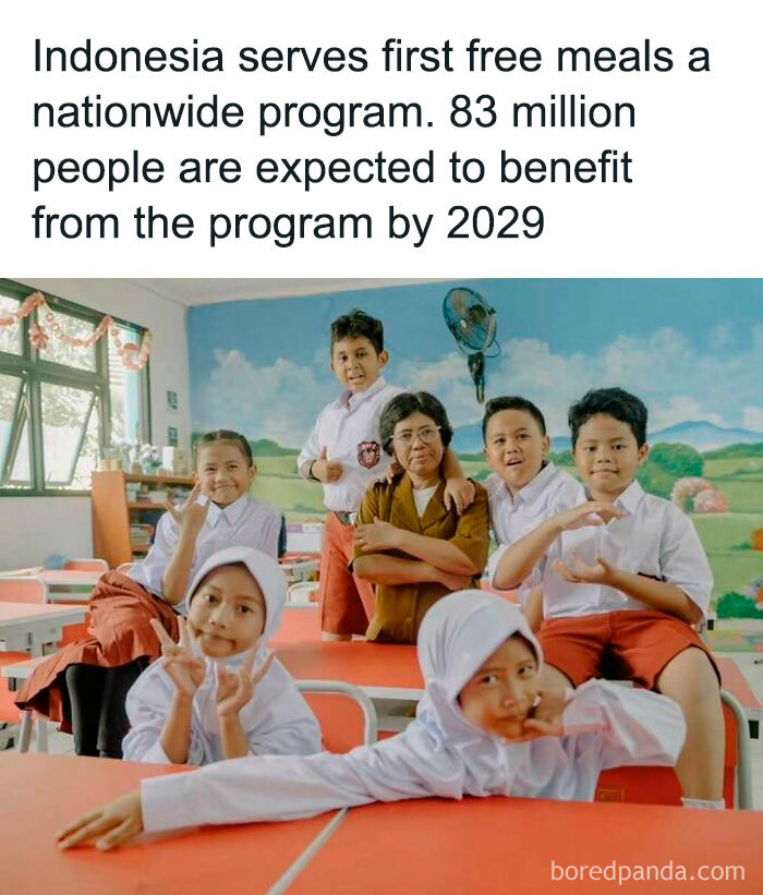 Children and a teacher smiling in a classroom, highlighting a positive program offering free meals in Indonesia.