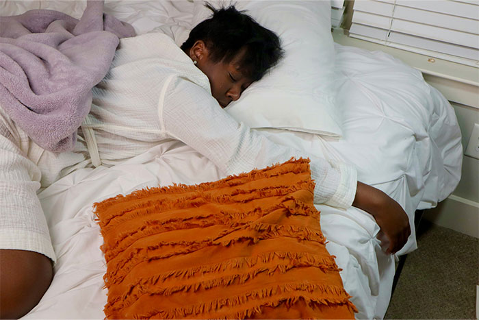 Person sleeping on a bed with white sheets and an orange pillow, symbolizing friendship ending stories.
