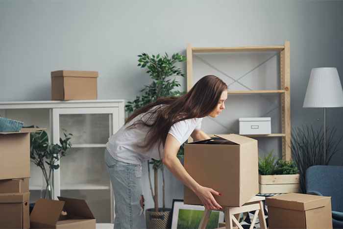 A woman packing cardboard boxes in a living room, organizing and arranging space.