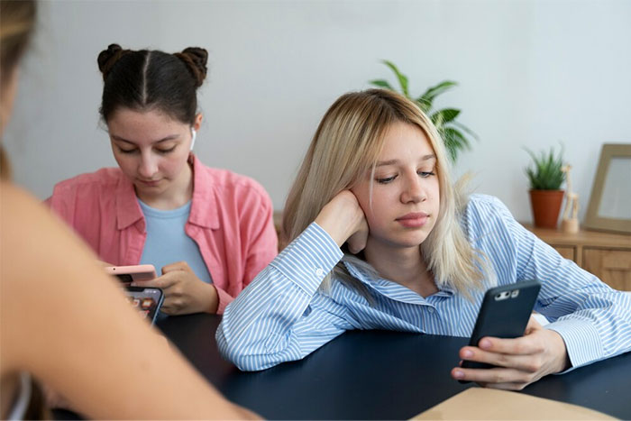 Two women on phones, one in a striped shirt, looking thoughtful, embodying friendship challenges.