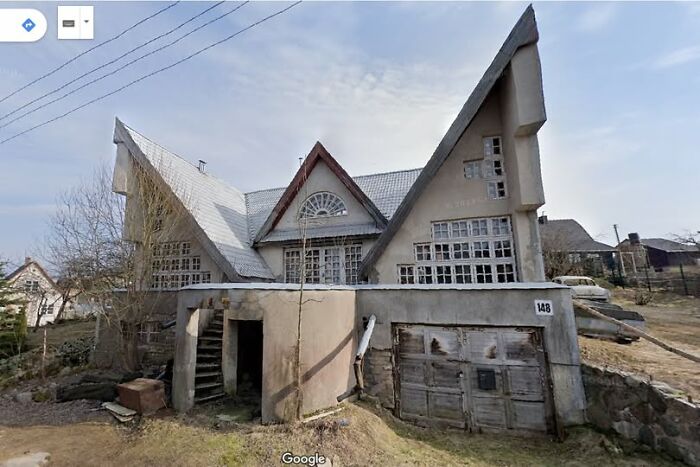Unique real estate property with sharp angular roof design and multiple large windows in a rural setting for sale