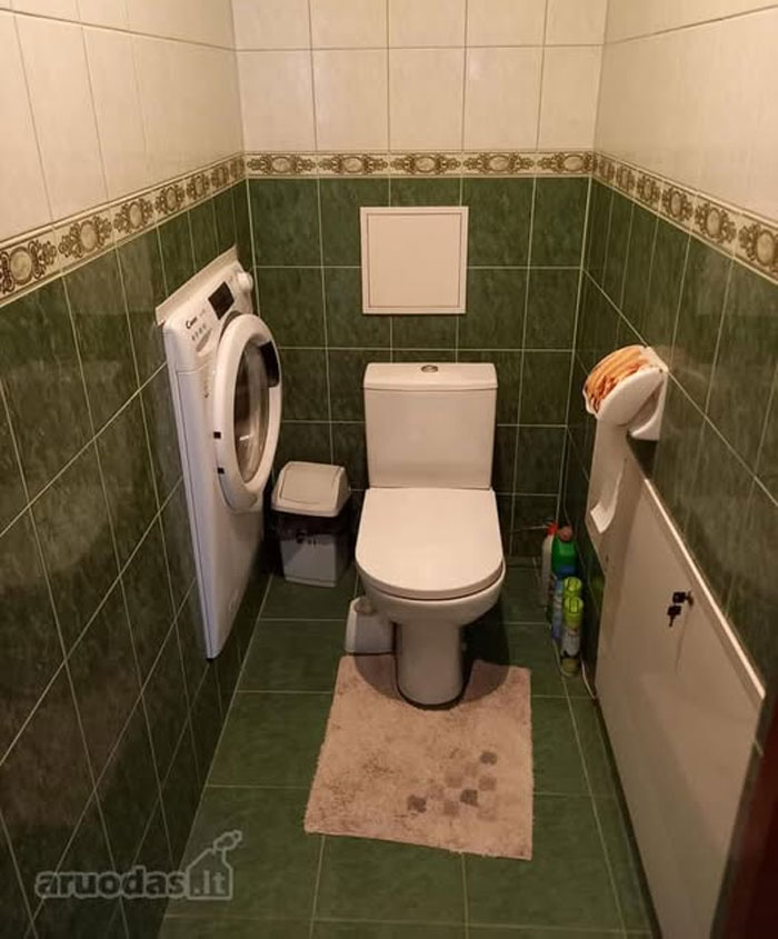 Small bathroom with green tiles includes toilet and washing machine in unusual real estate properties for sale.