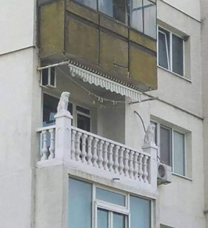 Balcony with ornate white railings and lion statues on top in a wild real estate property for sale.