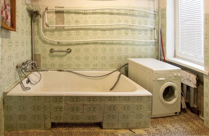 Vintage bathroom with patterned tiles, bathtub, and washing machine in one of the wildest real estate properties for sale.