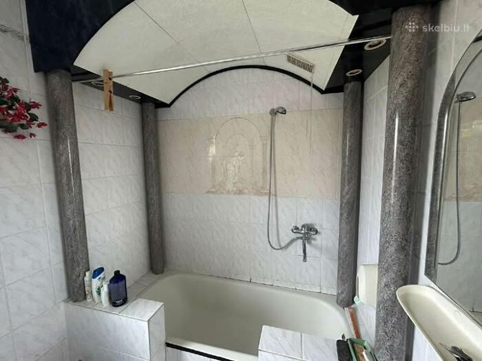 Bathroom in a wild real estate property featuring marble pillars, a bathtub, and a curved ceiling design with shower fixtures.