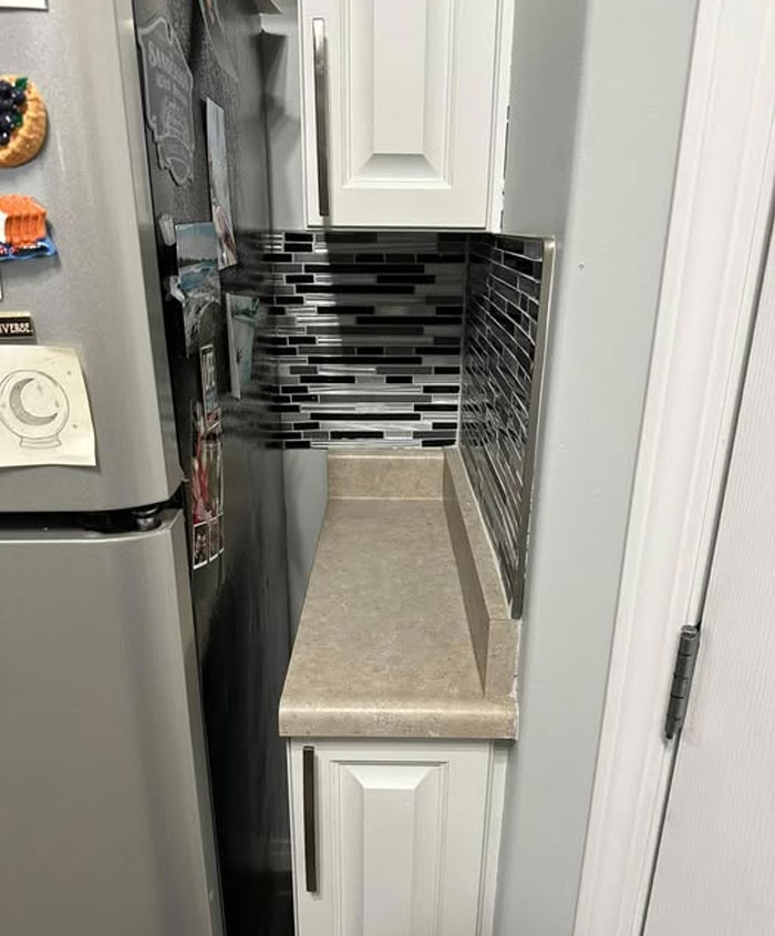 Narrow kitchen space with a fridge and small countertop, showcasing one of the wildest real estate properties for sale.
