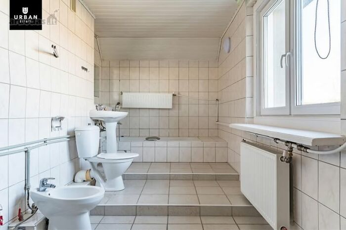 Modern bathroom interior of one of the wildest real estate properties for sale featuring white tiles and large window.