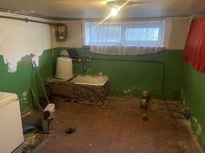 Basement room with old bathtub and green peeling walls in one of the wildest real estate properties for sale.