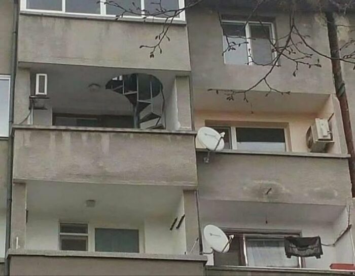 Balconies of a concrete apartment building featuring an unusual spiral staircase, showcasing wild real estate properties for sale.