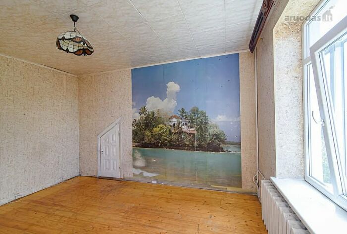Empty room with wooden floor and tropical island wall mural, an example of wild real estate properties for sale.