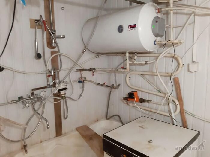 Utility room with an old water heater and exposed pipes in one of the wildest real estate properties for sale.
