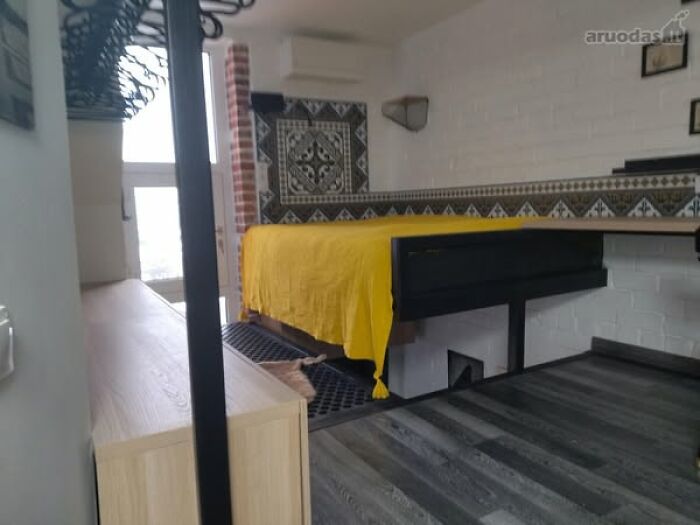 Modern real estate property featuring a unique suspended bed with a bright yellow cover and decorative tiles.