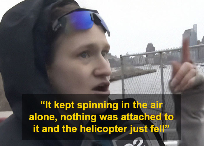 Witness recounts NYC helicopter crash, gestures near river with a dramatic expression, cityscape in background.