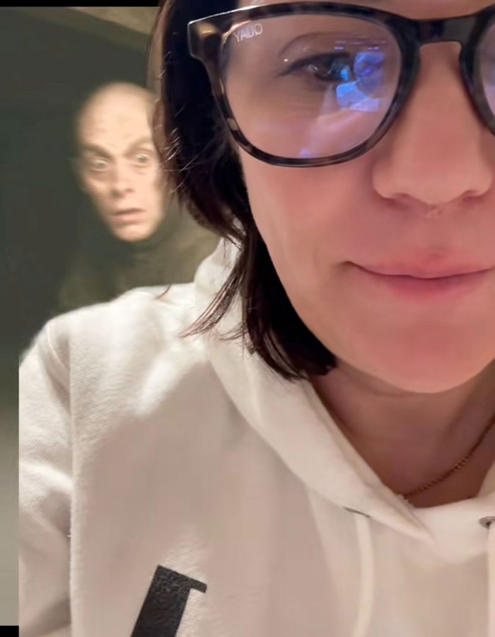 Woman in glasses surprised by unexpected attic discovery, with mysterious figure behind. Woman in glasses surprised by unexpected attic discovery, with mysterious figure behind.