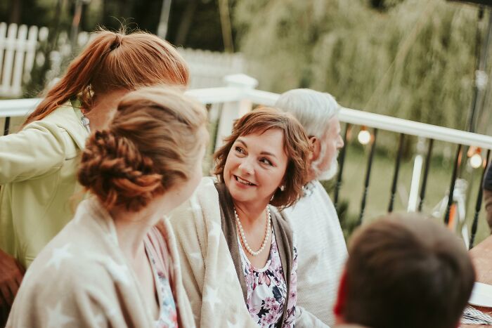 Women chatting outdoors, with one woman looking amused.