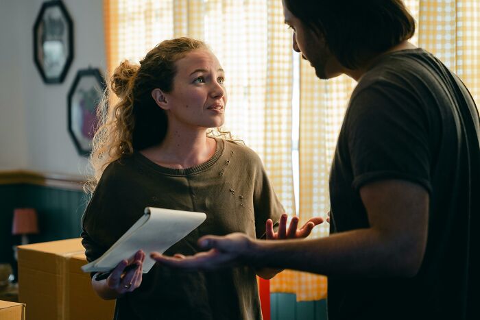 Woman discussing with a man in a home, holding a clipboard.