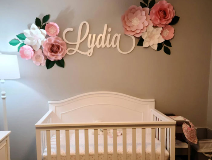 Nursery with floral decor and crib under the name Lydia, reflecting a personal name change theme.